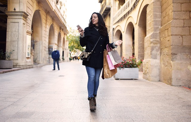 Une femme qui marque dans la rue face à nous avec des sac de shopping autour du bras